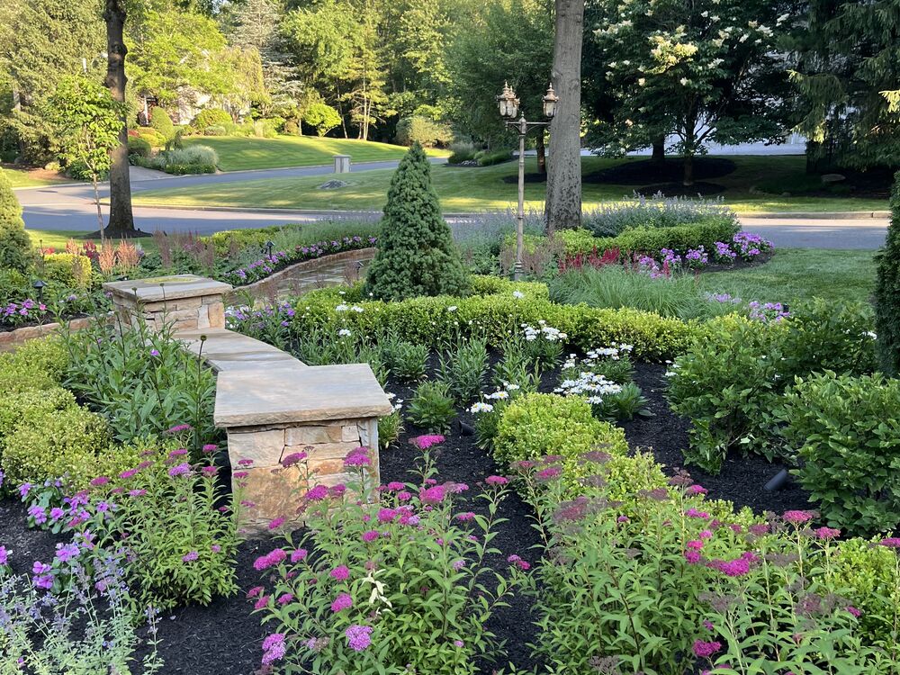Layered perennial garden bed with stone pillars and lamp post