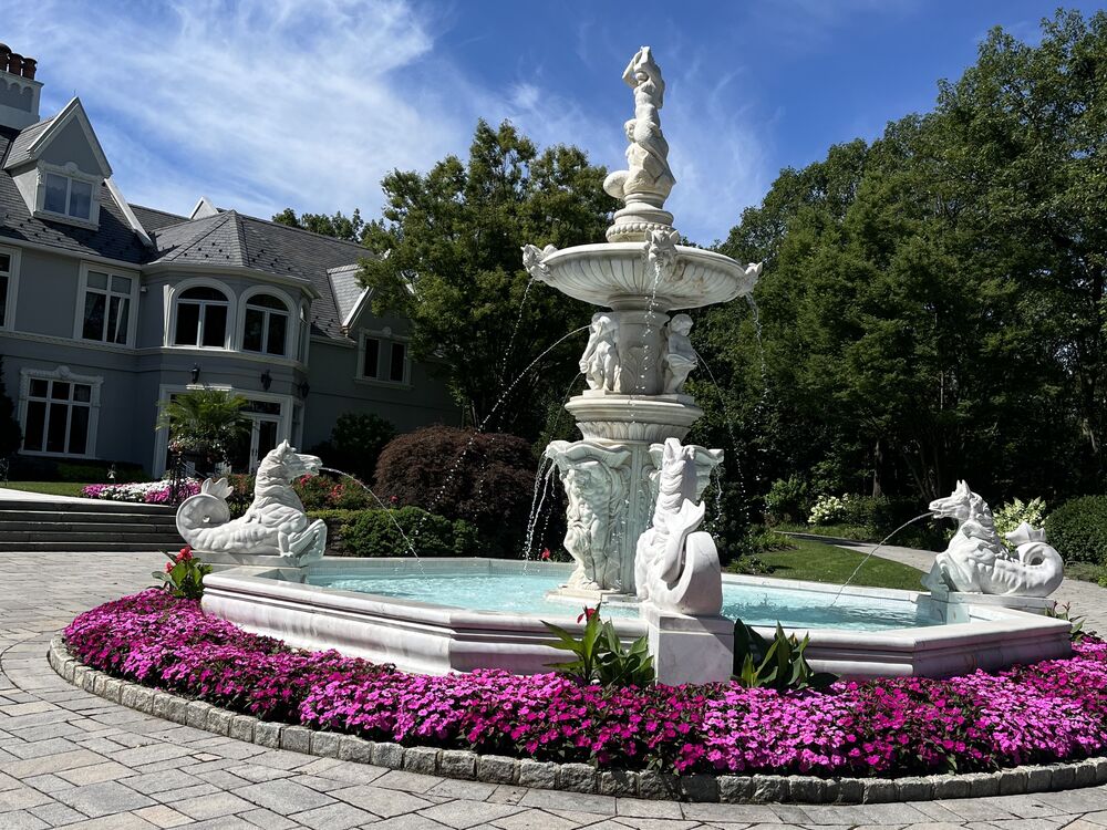 Stone fountain courtyard with purple annual flower border