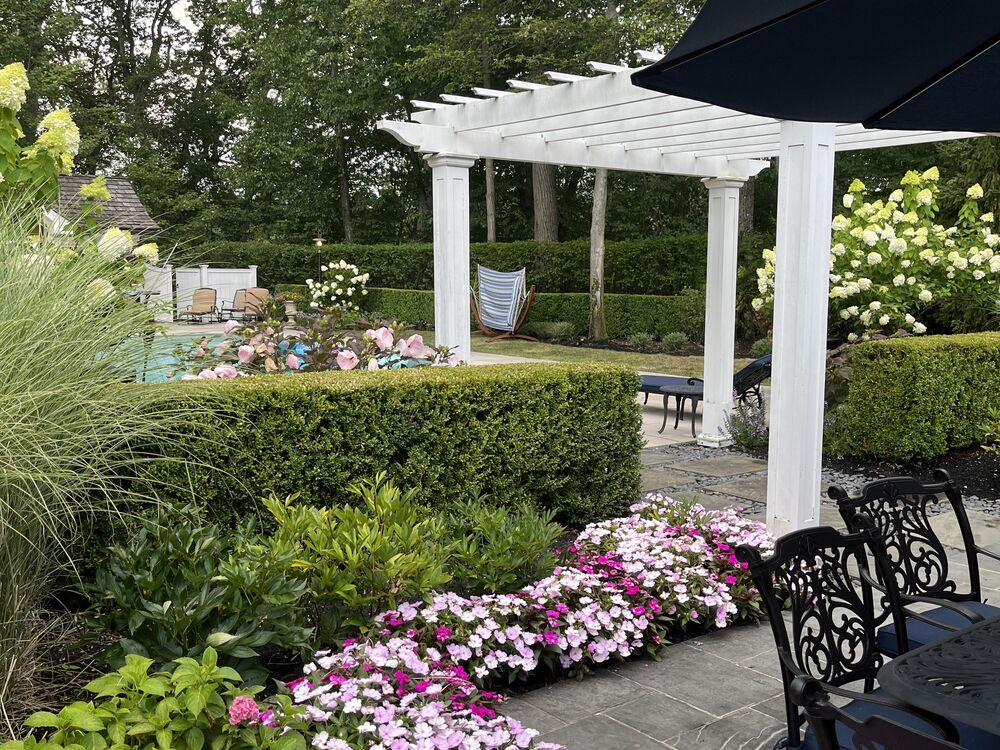Pergola-covered patio with a dense flowering perennial border