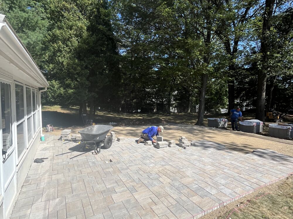 Large paver patio being installed under a deck